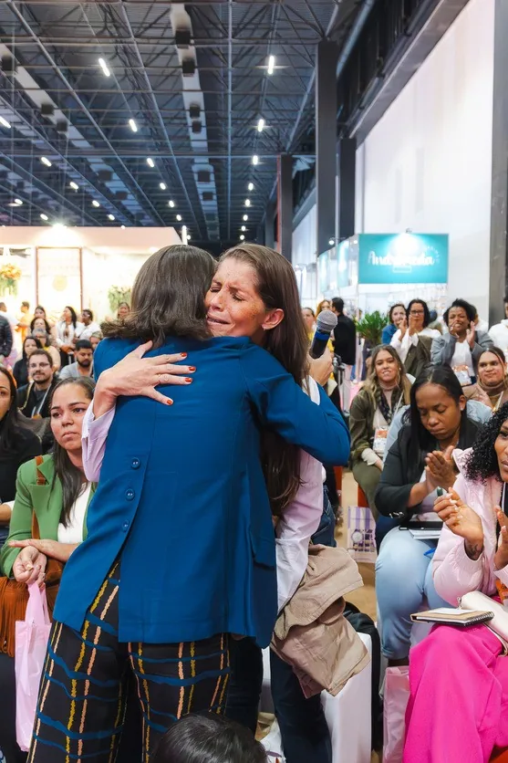 Ana Bauer abraçando uma aluna na feira